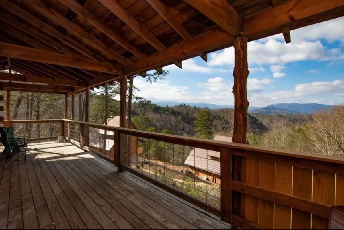 A spacious wooden deck with mountain views and surrounding trees, designed for relaxing, enjoying nature, and gathering with friends. The tranquil setting is ideal for al fresco dining and soaking in the scenery after a shared meal.